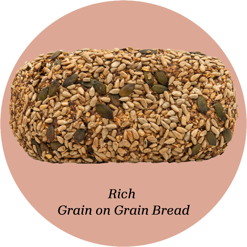 Loaf of gluten free bread with seeds on a pink background, labeled 'Rich Grain on Grain Bread'.